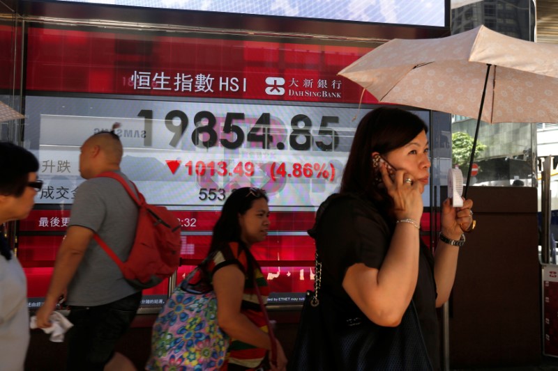 A woman is seen by a stock market board in Hong Kong