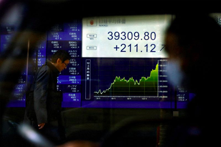 An electronic screen displaying Japan’s Nikkei share average and stock prices is seen through a car as the share average hits a record high in Tokyo.