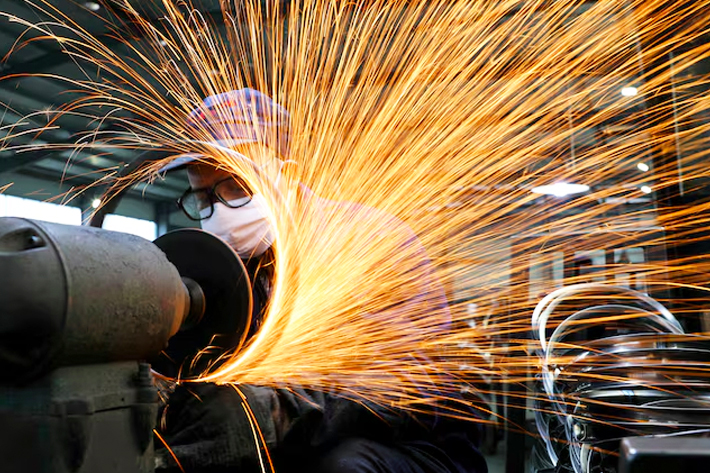 A worker wearing a face mask works on a production line manufacturing bicycle steel rim at a factory.