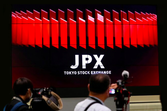 TV camera men wait for the opening of market in front of a large screen showing stock prices at the Tokyo