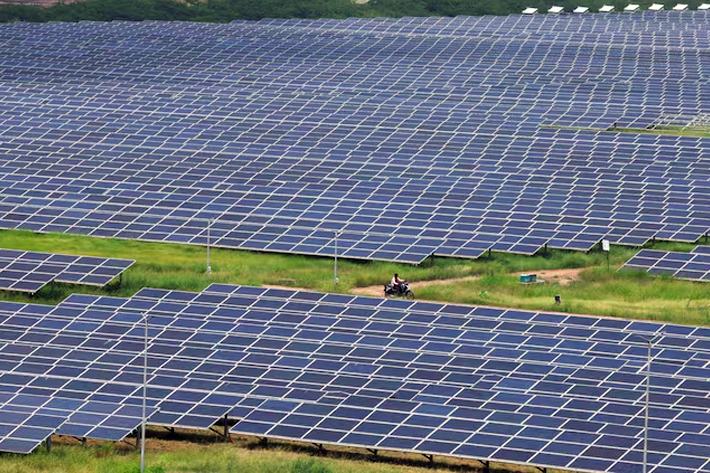 A man rides a motorcycle along the solar panels in Gujarat Solar Park also called Charanka Solar Park at Patan district in Gujarat,