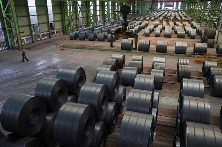 A worker walks by steel rolls at the Chongqing Iron and Steel plant in Changshou, Chongqing, China.