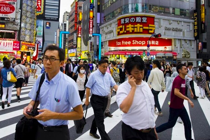 People cross a busy junction outside the nightlife district in Shinjuku in Tokyo.