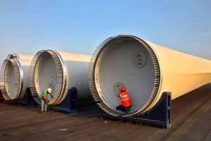 Workers prepare blades of a power-generating windmill turbine for transport, at the plant of Adani Green Energy Ltd