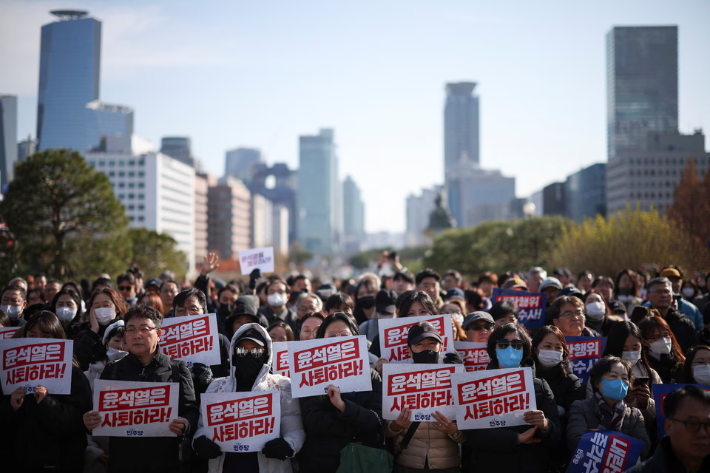 Protesters hold up signs that read 