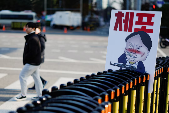 A pedestrian walks past a banner denouncing South Korean President Yoon Suk Yeol, who declared martial law, which was reversed hours later, in front of the National Assembly in Seoul, South Korea, December 9, 2024. The slogan reads, 'arrest'