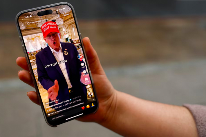 A woman poses with her smartphone displaying the @realdonaldtrump TikTok page, in Washington, U.S.